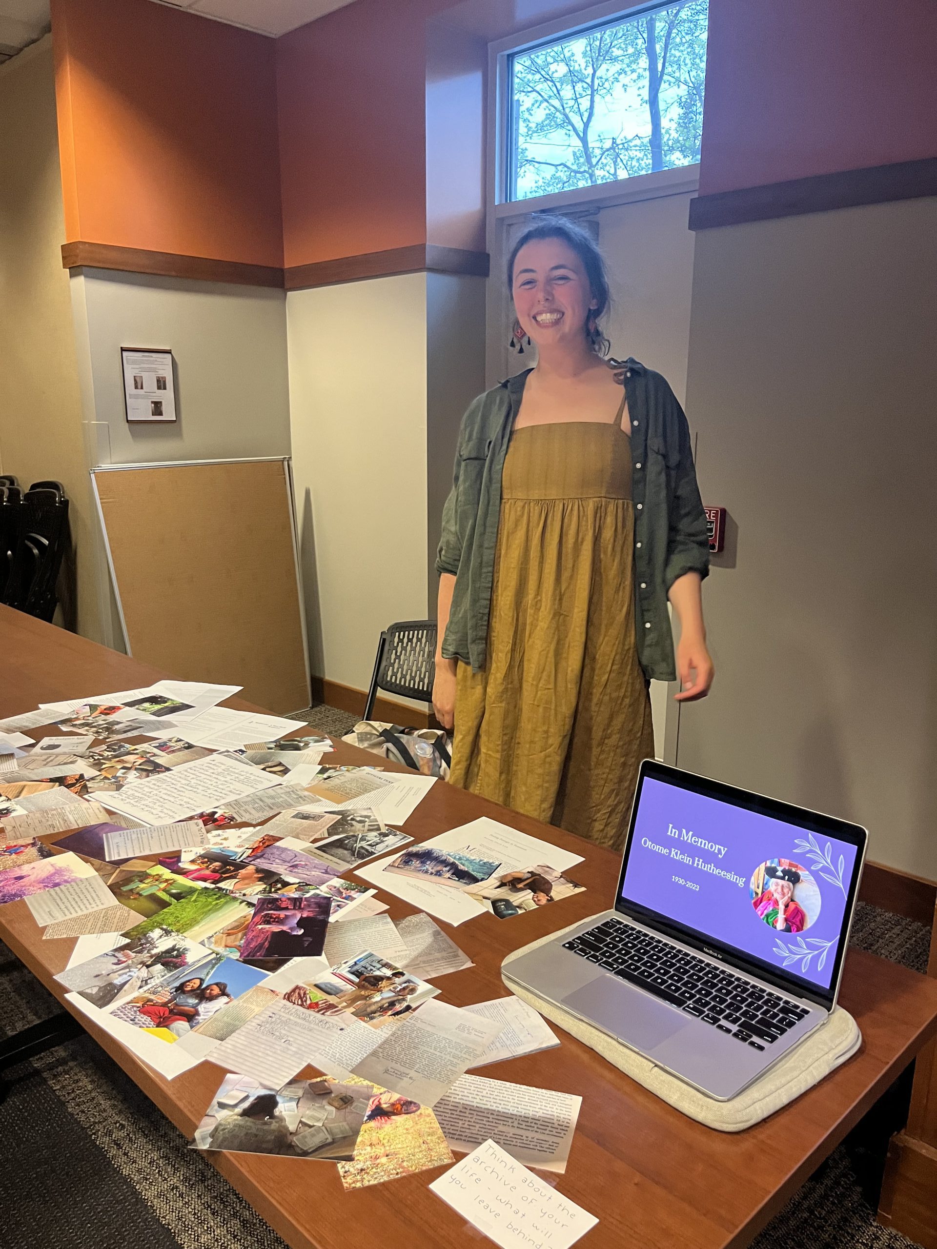 Bella Kirchgessner standing in front of a table display with photos and articles as part of her senior project