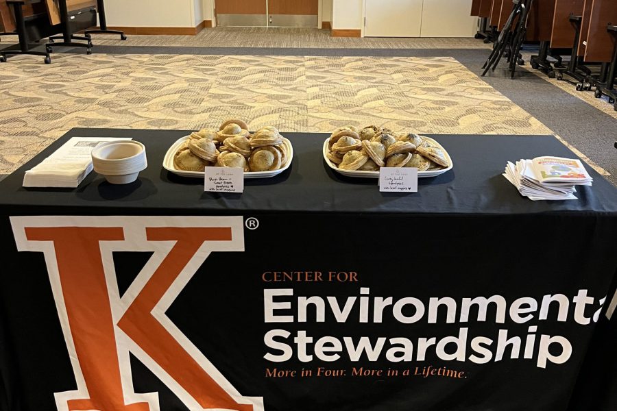 Black table cloth with an orange K that reads Environmental Stewardship. Pastries are on top of the table