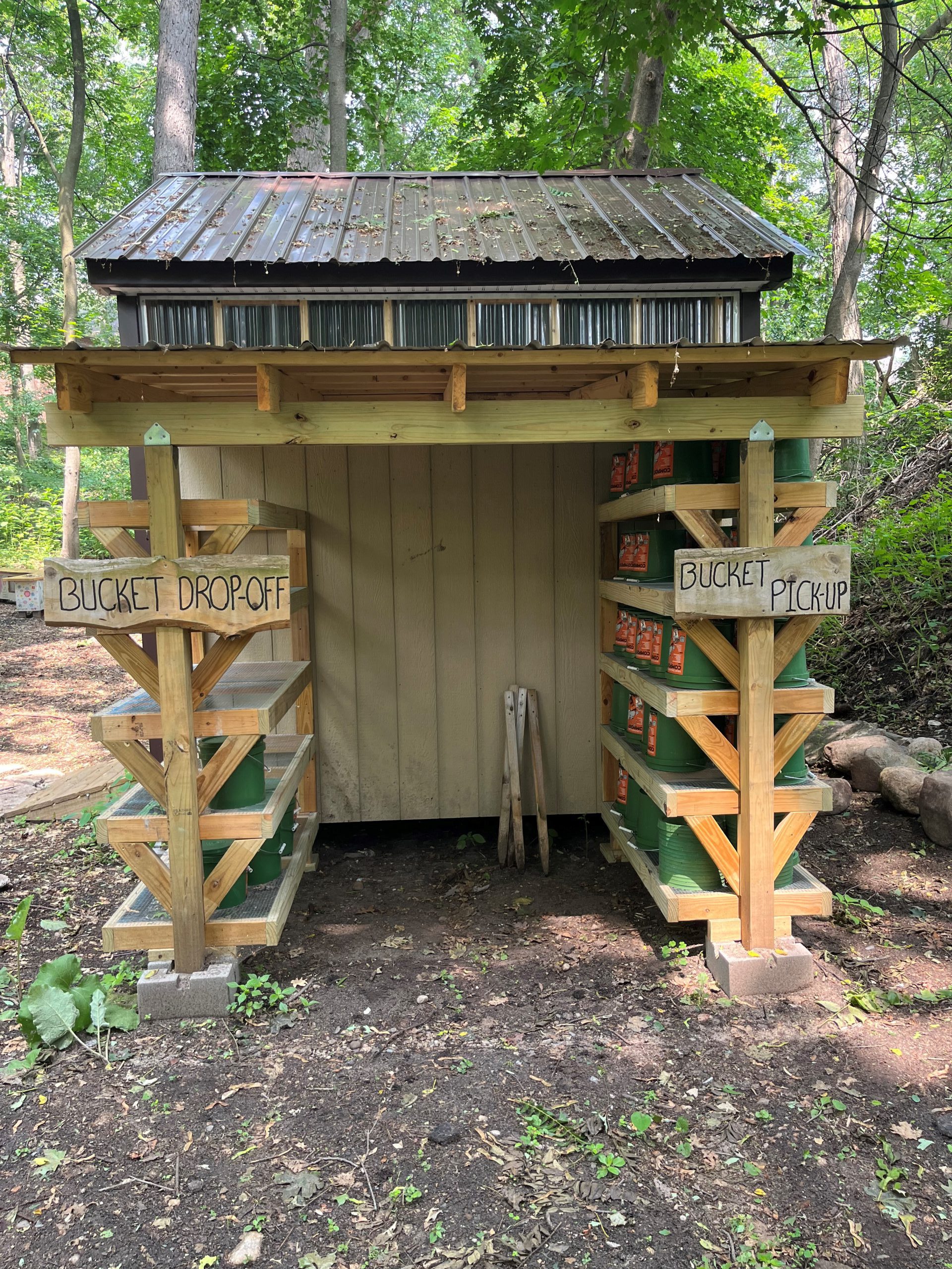 Composting shed with bucket drop off and pick up signs