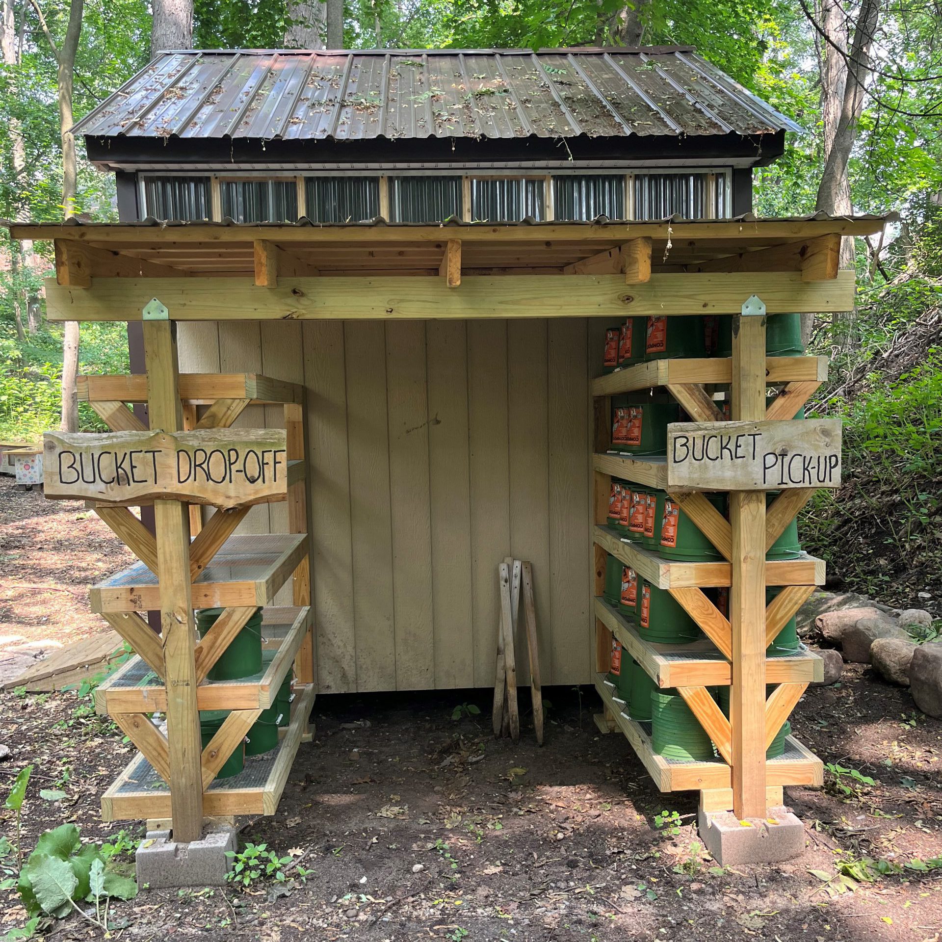 Composting shed with bucket drop off and pick up signs