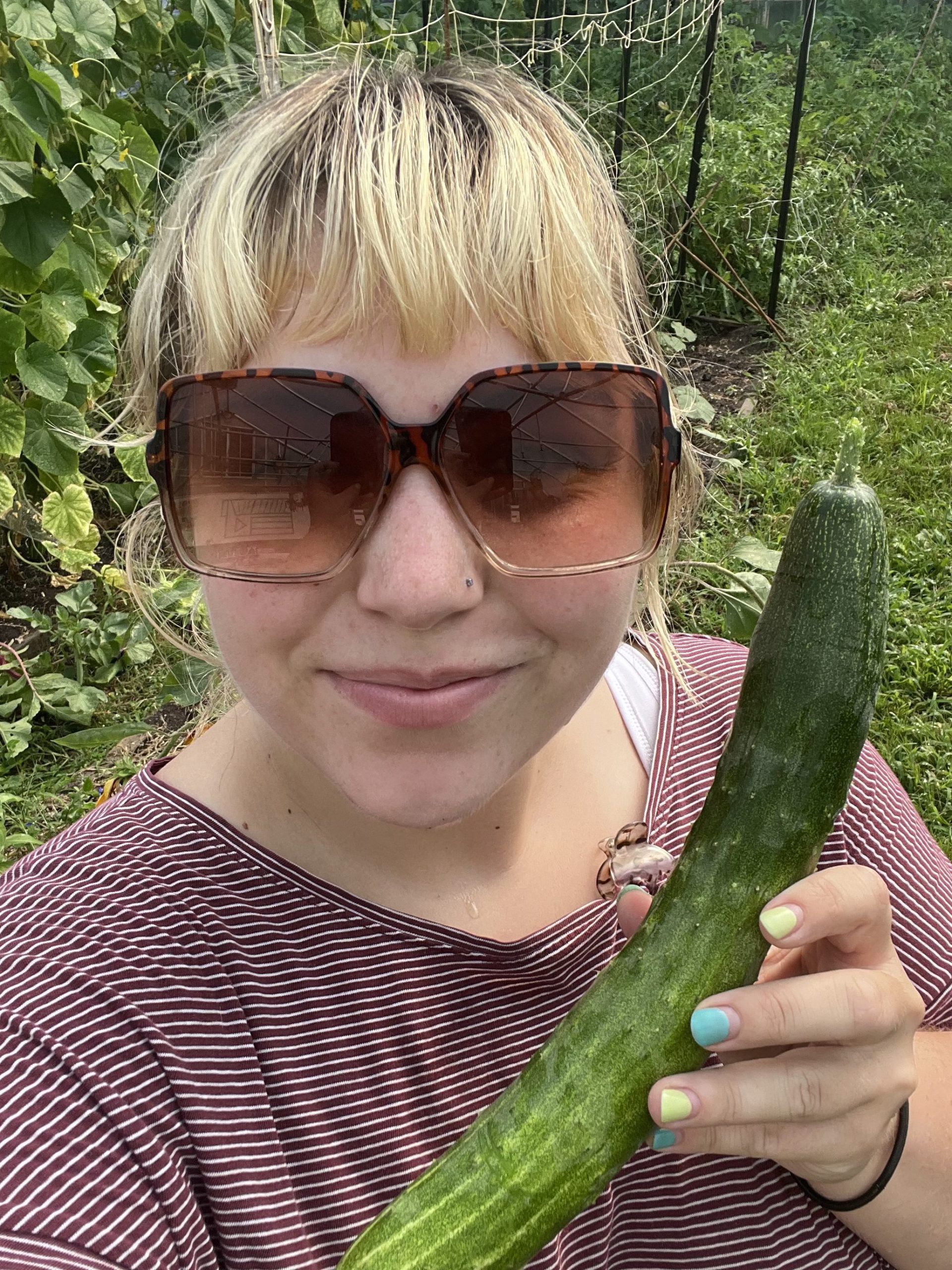 Zoe Wilson holding a cucumber grown in the Hoop House