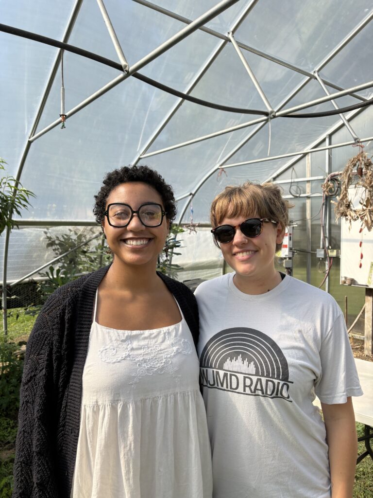 Two smiling students inside a Hoop House