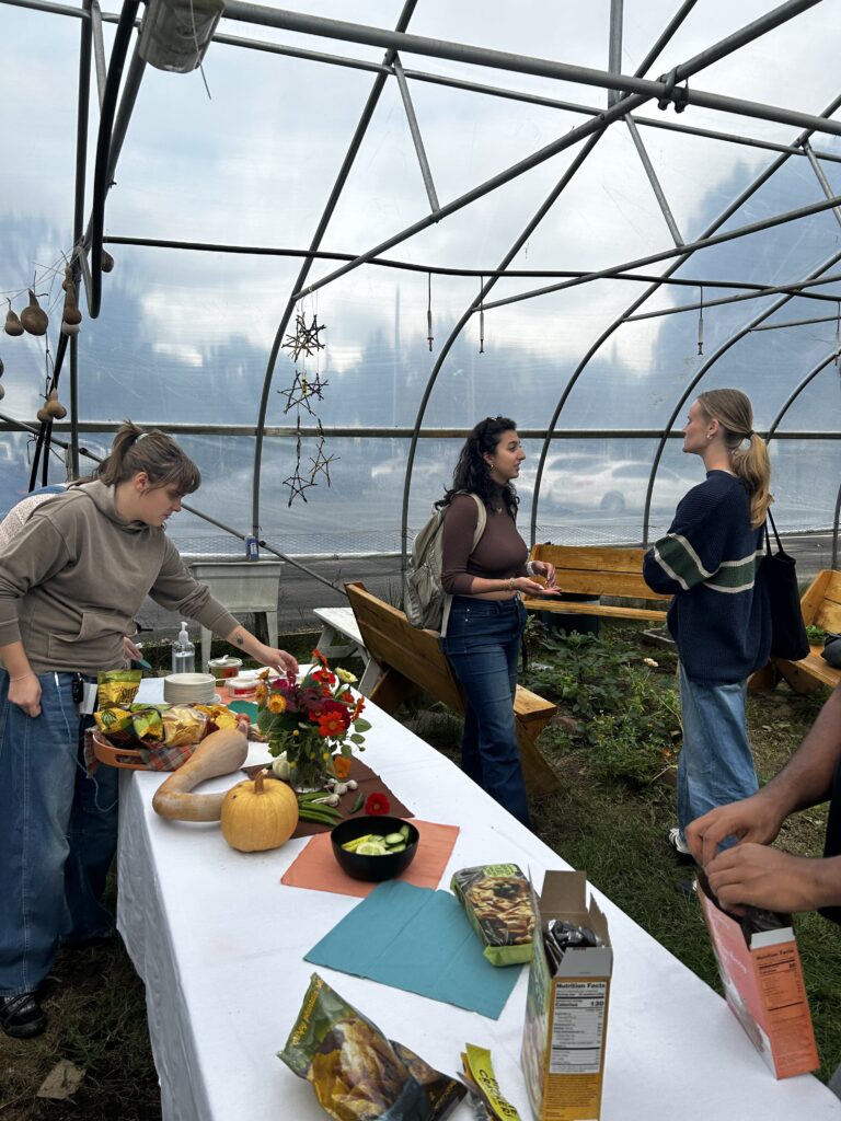 People hanging around a table inside a hoop house