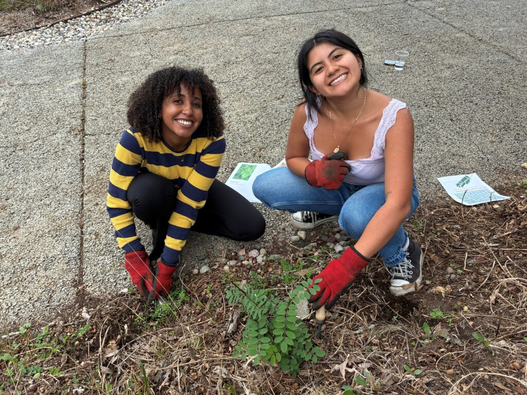 Two students smiling with plants