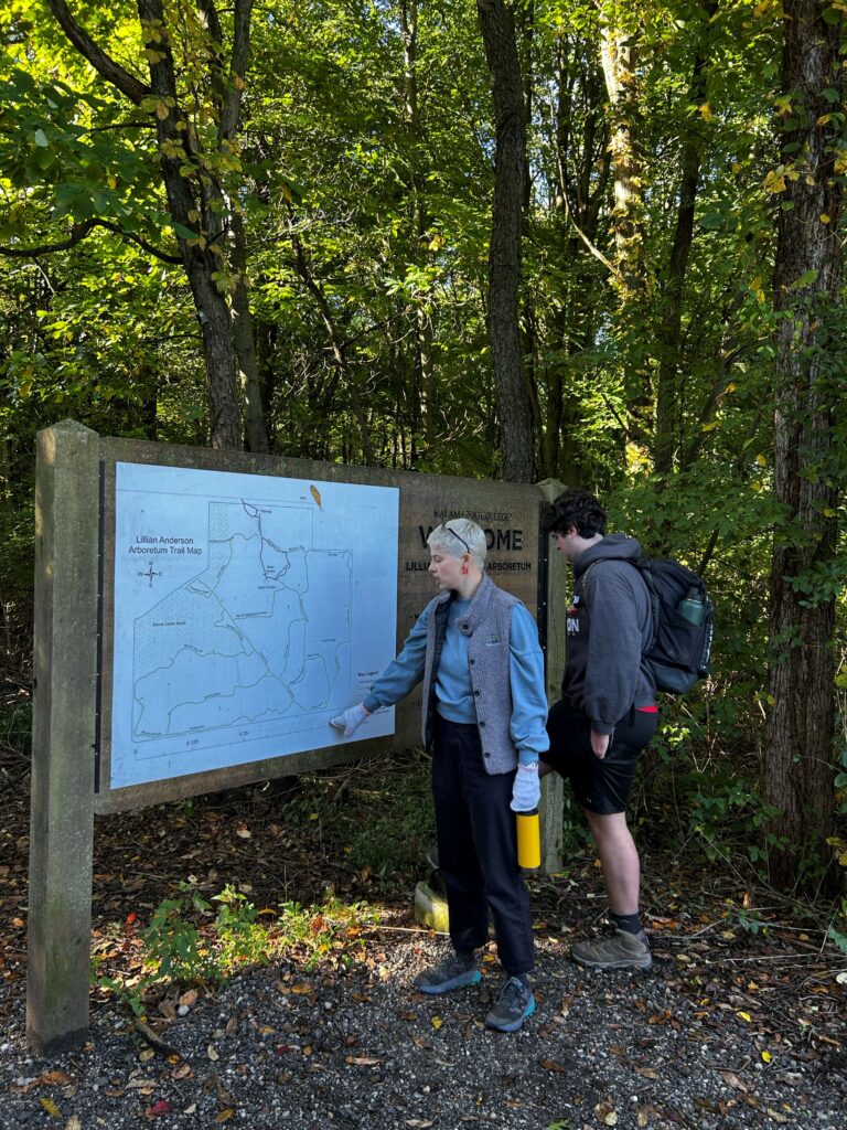Two people in front of a large trail map sign